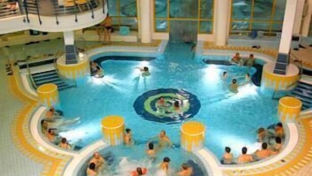 Una amplia piscina interior con varias pistas de natación y una fuente central.