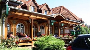 Una casa tradicional de madera con techo de tejas, un porche cubierto y un jardín con flores y plantas.