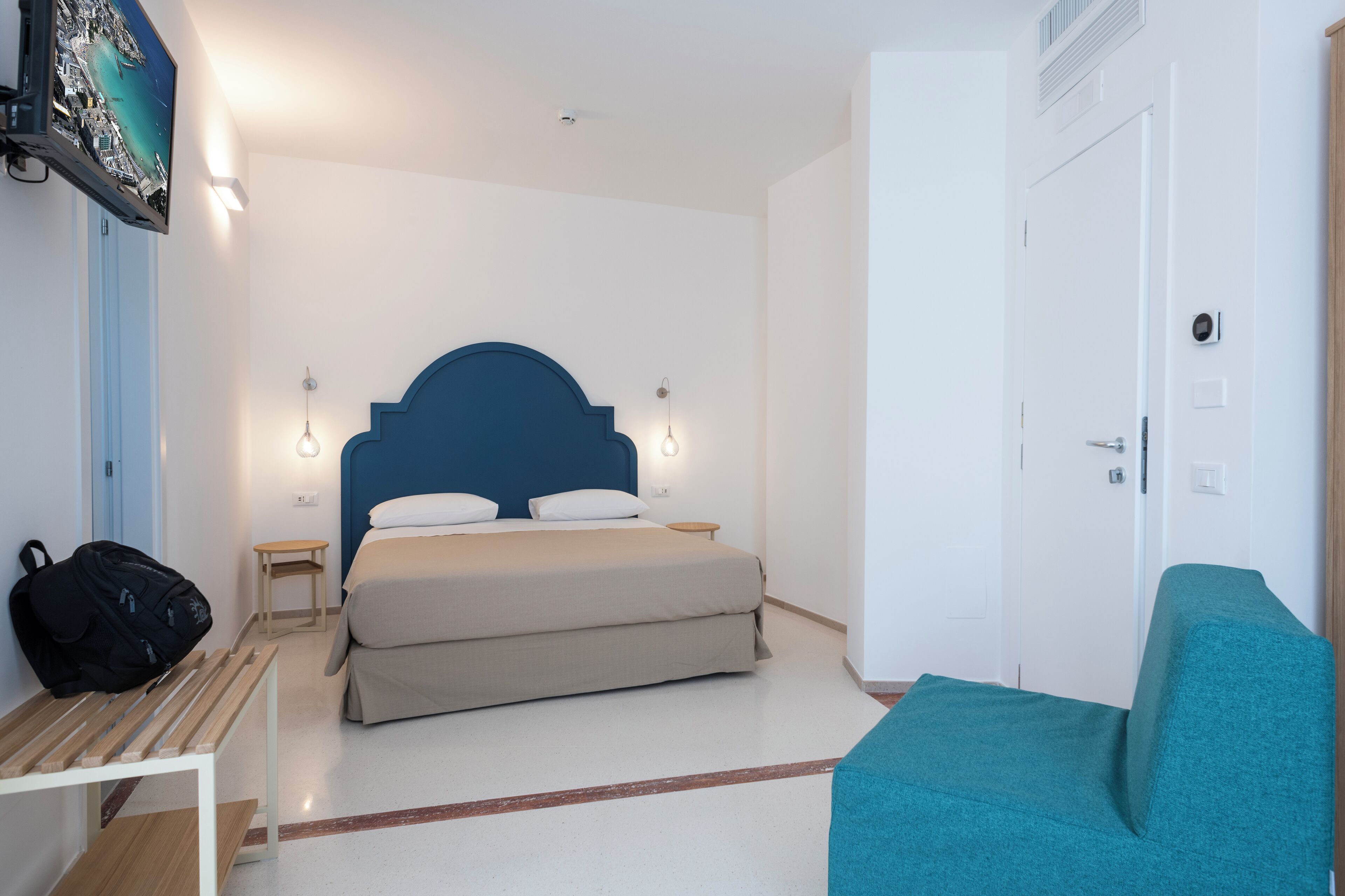 Ein Hotelzimmer mit einem Bett, einem Schreibtisch, einem Stuhl, einem an der Wand befestigten Fernseher und einer Tür.