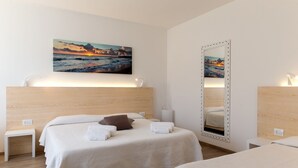 A hotel room with a bed, a bedside table, a mirror, and a painting of a sunset over the sea. - Hotel Albània (Otranto)