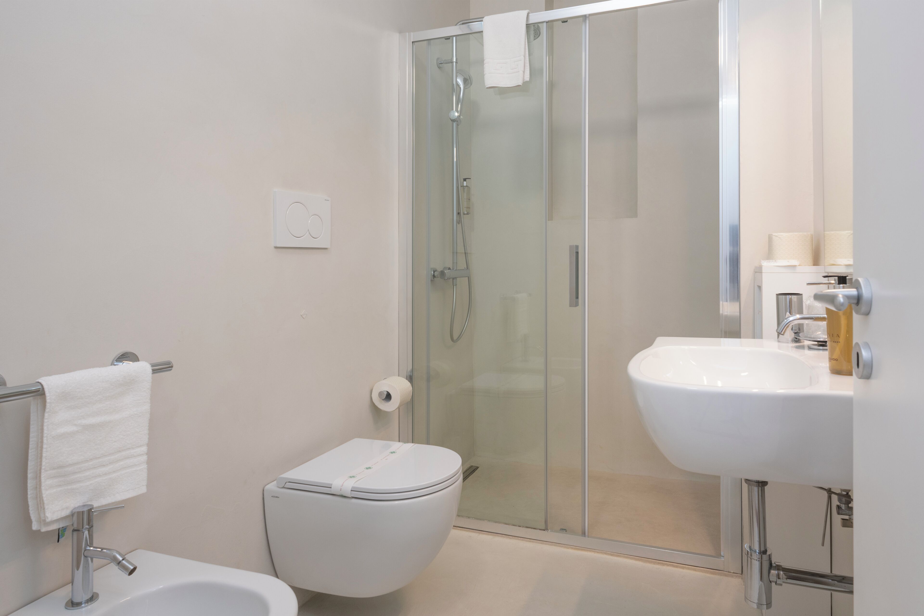 A modern bathroom with a glass-enclosed shower, a white toilet, and a sink with a mirror.