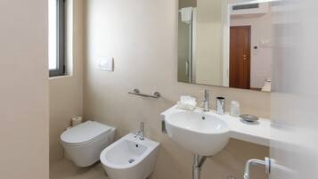 A modern bathroom with a toilet, bidet, and a large sink.