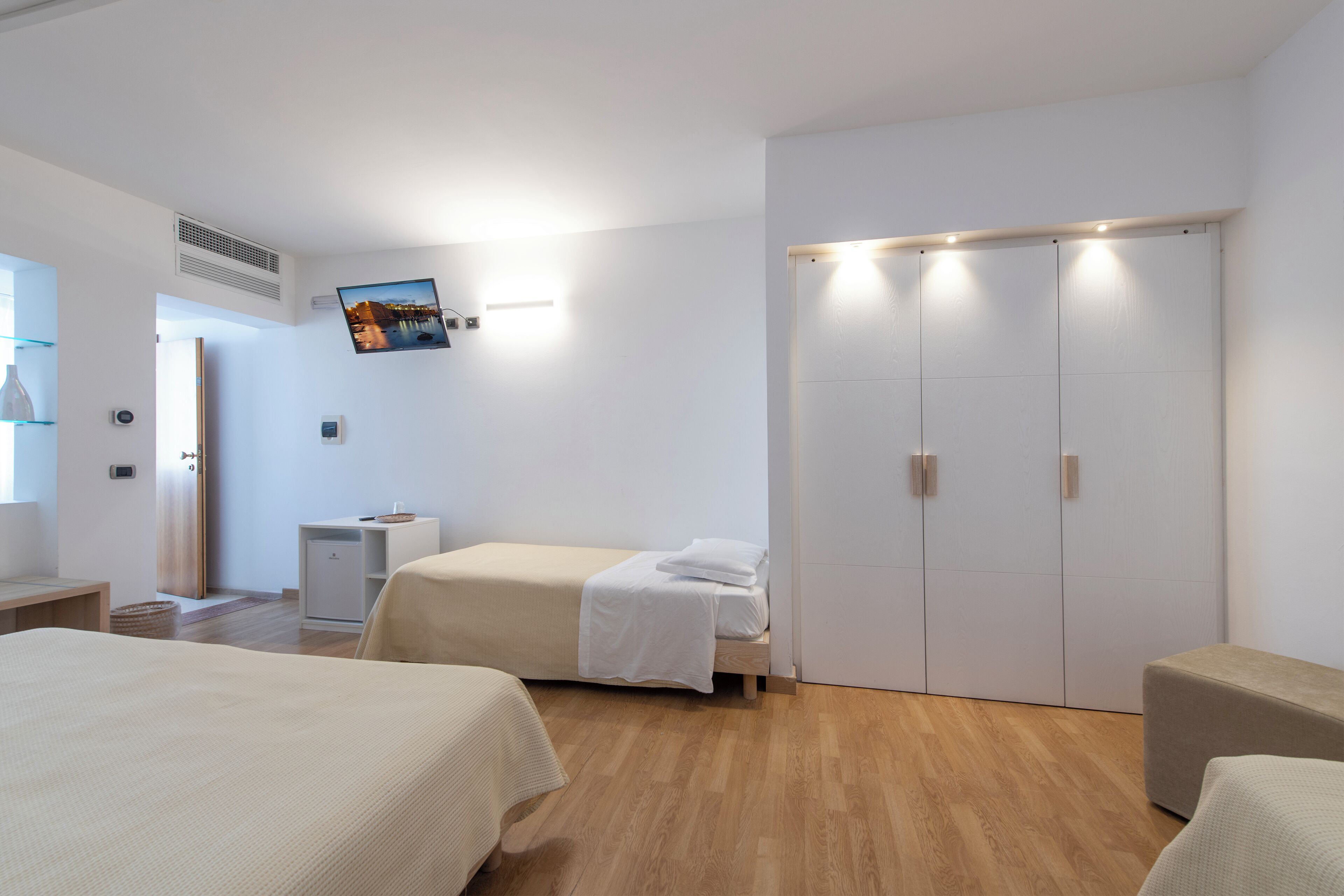 Une chambre d’hôtel moderne équipée de deux lits, d’une armoire, d’un bureau et d’une télévision.