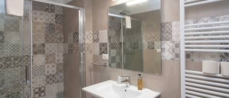 A bathroom with a shower, sink, and towel rack.