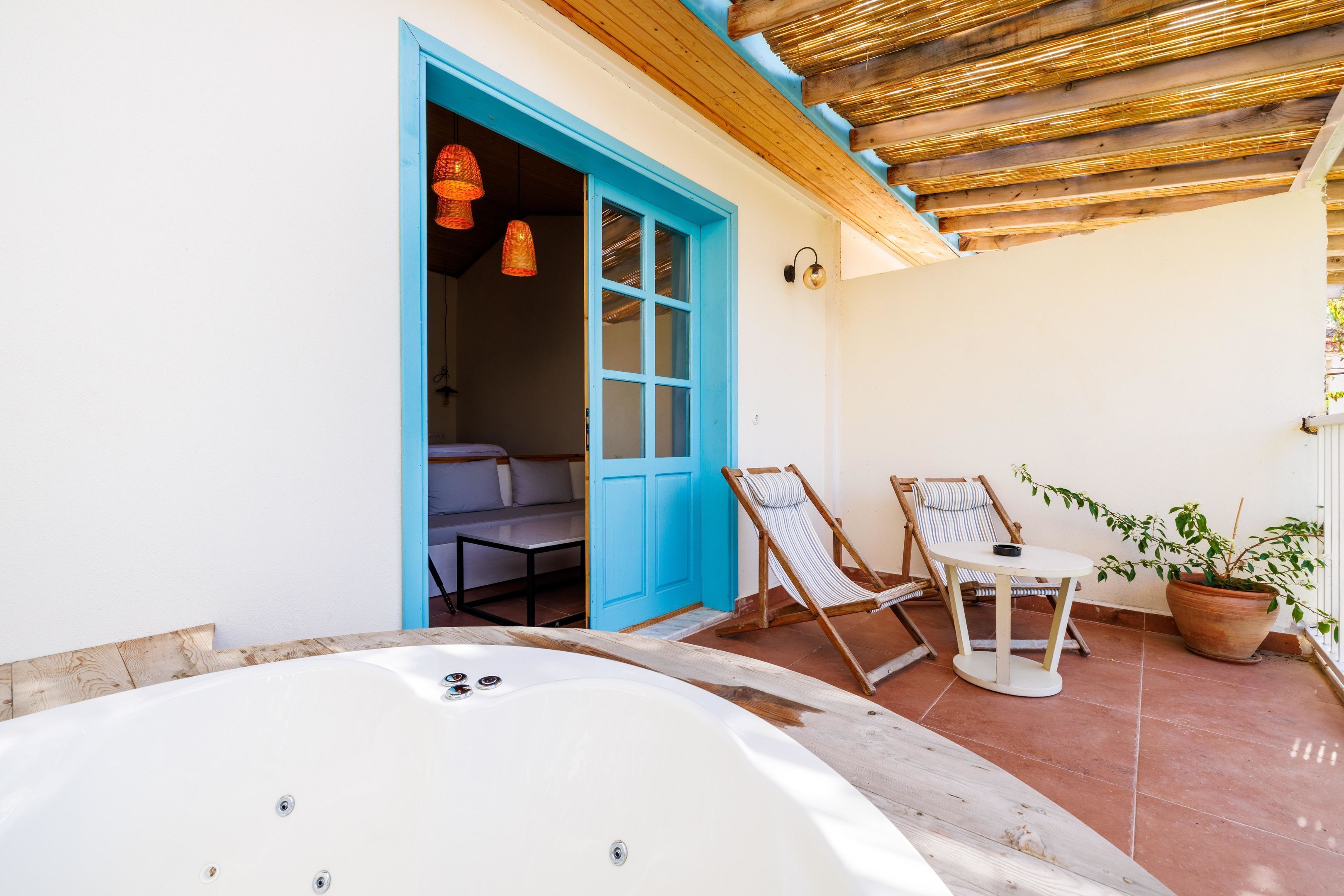 Un espacio de spa con un jacuzzi, una puerta azul y una zona de estar con mesa y sillas.