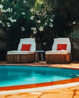 Un área junto a la piscina con dos sillones de descanso y una mesita.
