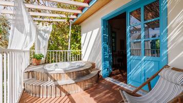 Una bañera de hidromasaje exterior de madera con escalones, una puerta azul y una silla a rayas.