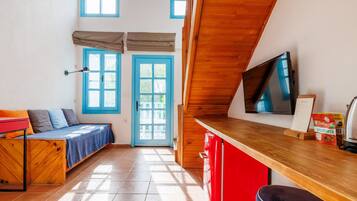 A cozy room with a bed, a TV, a wooden desk, and a red chair.