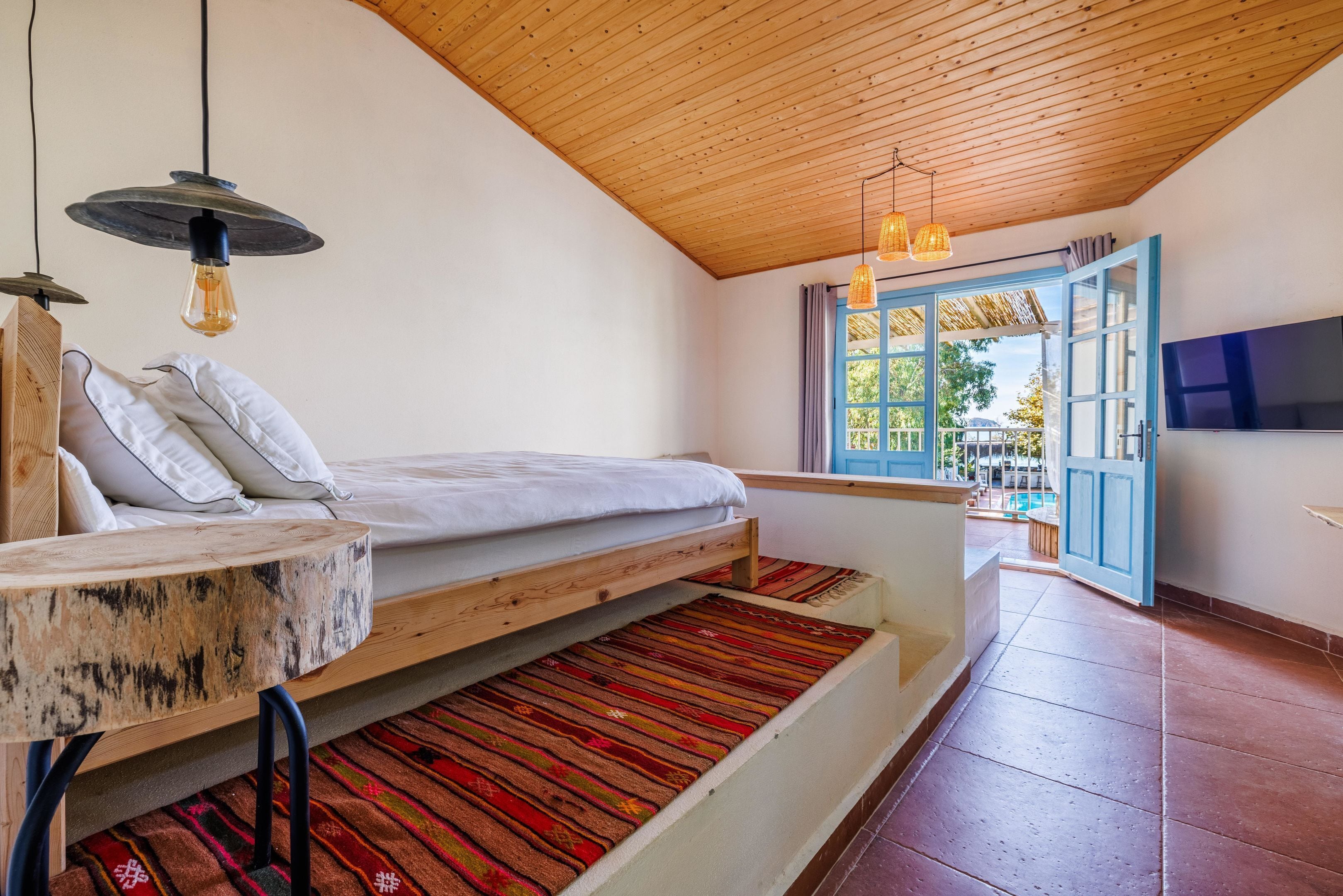 Un dormitorio con cama, un banco de madera, una televisión y vistas al exterior.