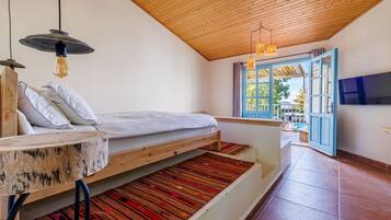 Un dormitorio con cama, un banco de madera, una televisión y vistas al exterior.