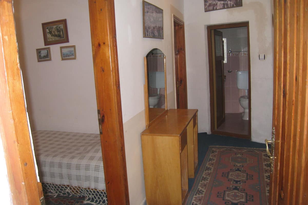 A hallway with a wooden door, a mirror, and a bed with a checkered bedspread.
