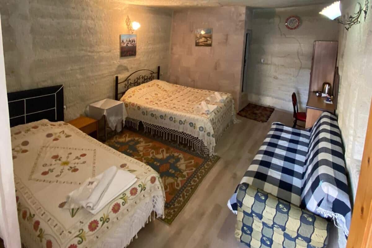 A small, cozy room with two beds, a desk, and a chair.