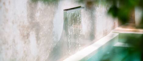 A modern indoor pool with a clear water feature and a textured wall.