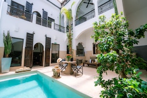 Un cortile con piscina, area salotto all'aperto e una scala che conduce ai piani superiori.