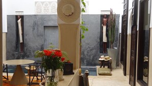 A courtyard with a table, a vase of flowers, and a statue. - Riad Dar Massai (Marrakech)