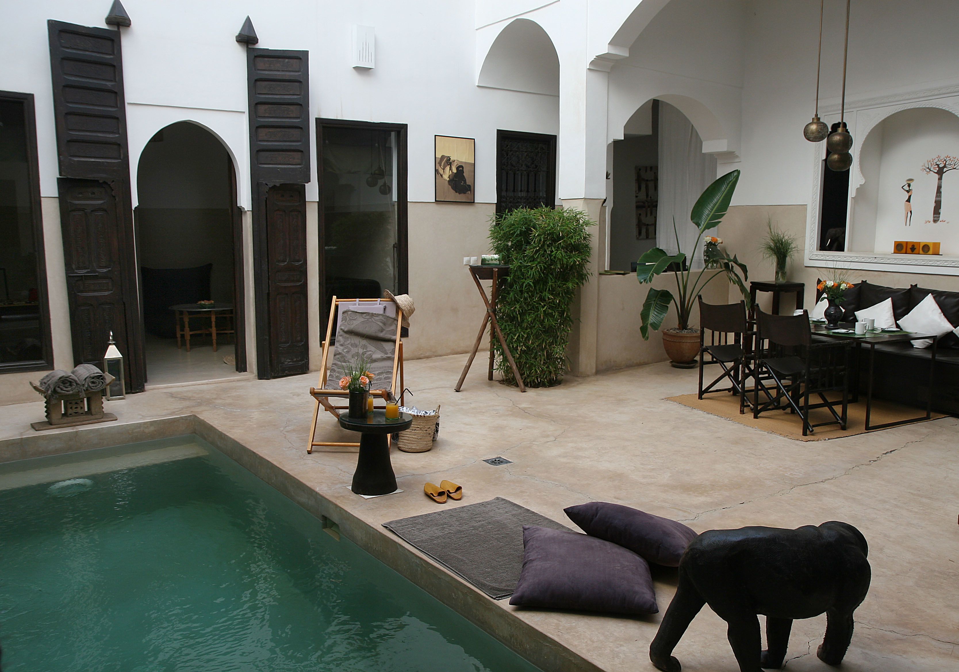 Une cour avec une piscine, un espace salon et un coin repas.