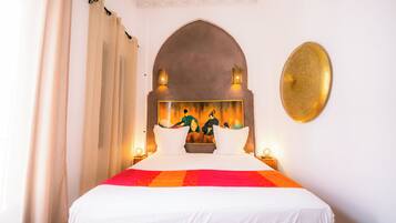 Una habitación de hotel con una cama grande, un techo abovedado decorativo e iluminación empotrada en la pared.