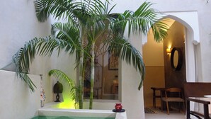 A spa area with a hot tub, a wooden chair, and a table. - Riad Dar Massai (Marrakech)
