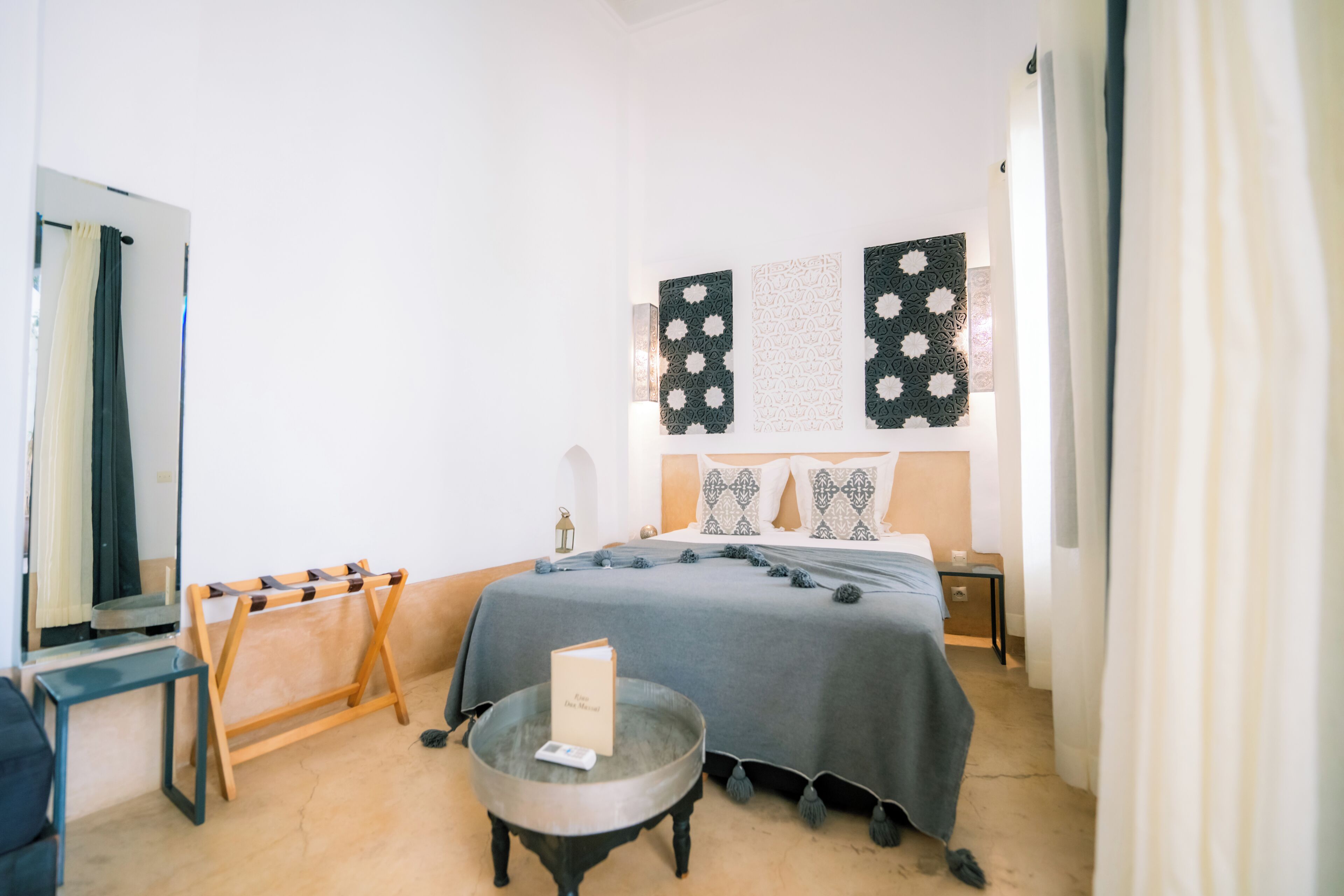 A bedroom with a bed, bedside table, lamp, and wall decorations.
