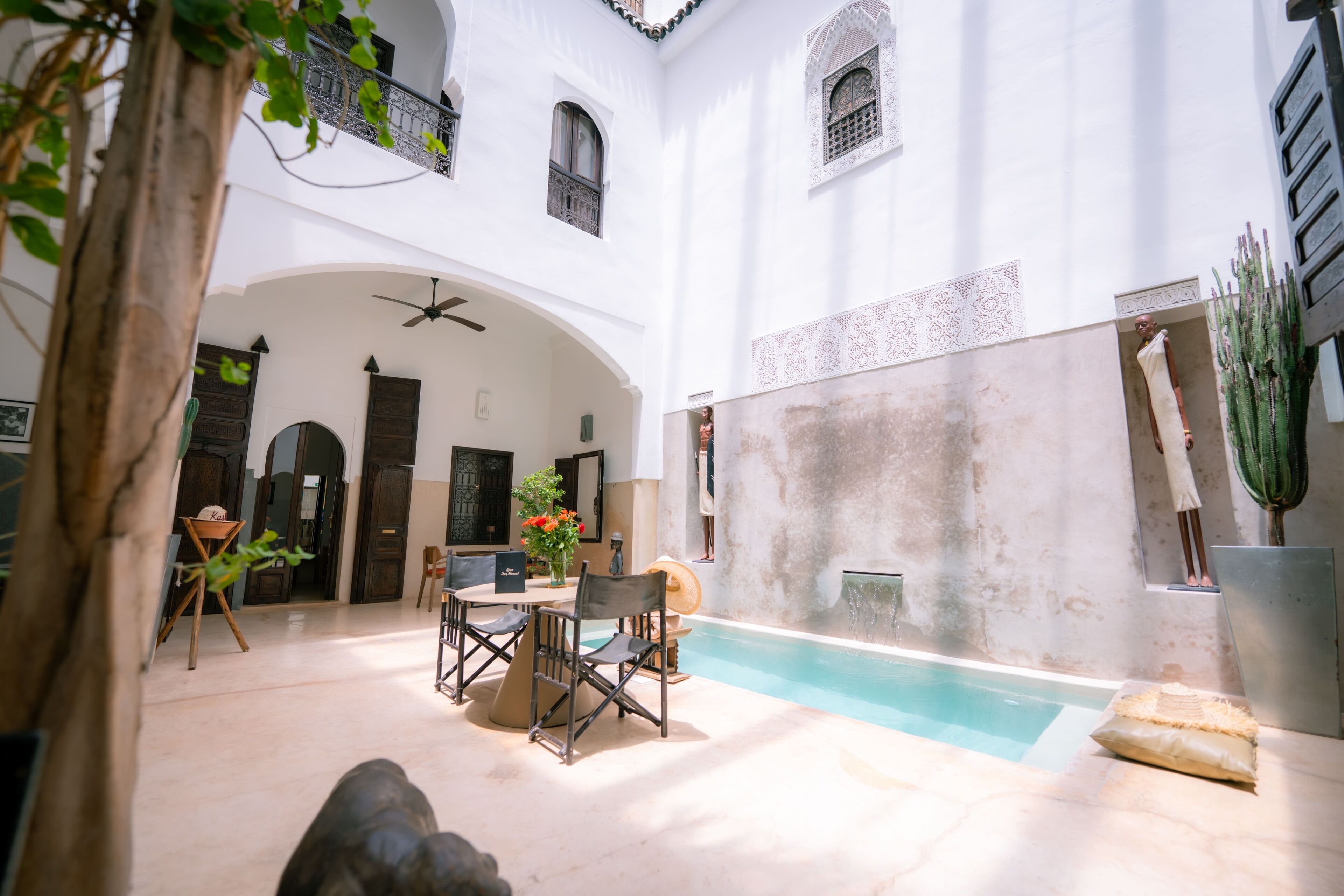 A courtyard with a pool, outdoor seating, and a statue.
