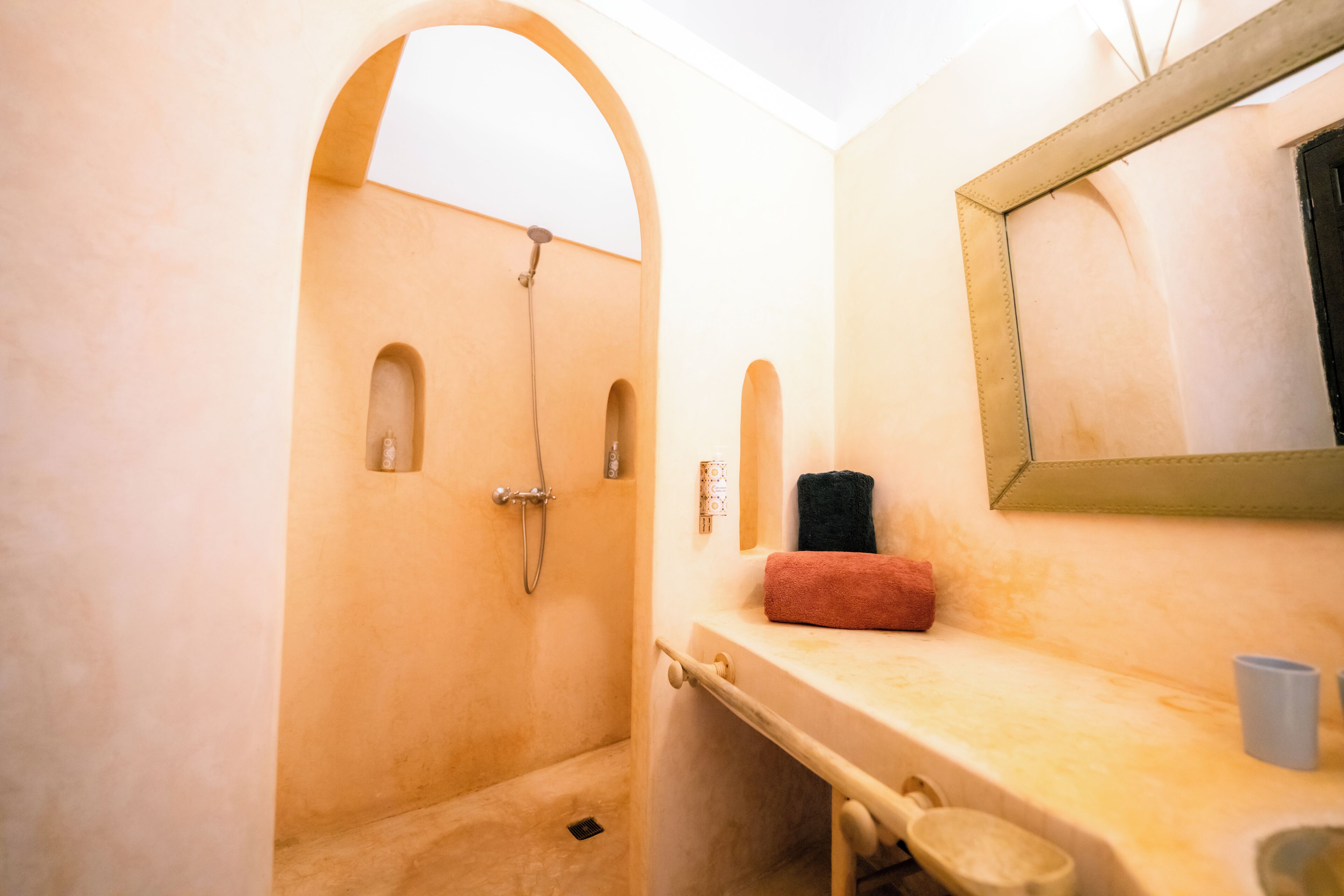 Un baño con ducha, lavamanos, espejo y toallero.