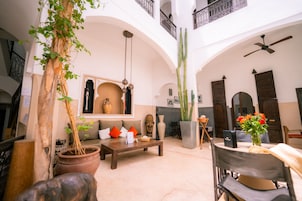 Un'ampia area interna con soffitto alto, caratterizzata da un tavolino in legno, una pianta in vaso e un grande cactus.