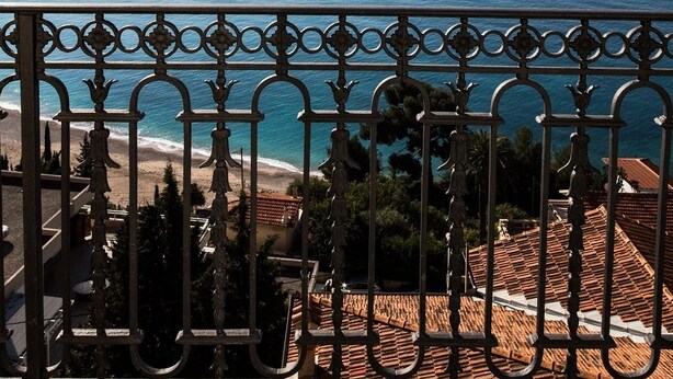 Un balcón con vista al mar y una isla distante.