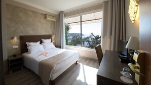 Habitación de hotel con una cama grande, un escritorio con lámpara, televisión y vistas al exterior.