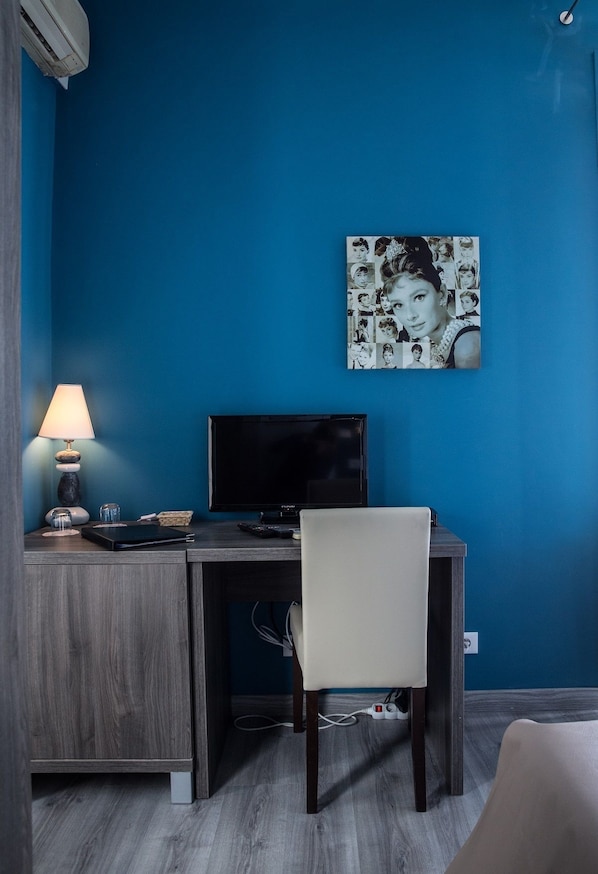Une pièce avec un mur bleu, un bureau avec un ordinateur, une lampe et une chaise.