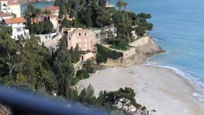 Zona costera con edificios rodeados de árboles y una playa.