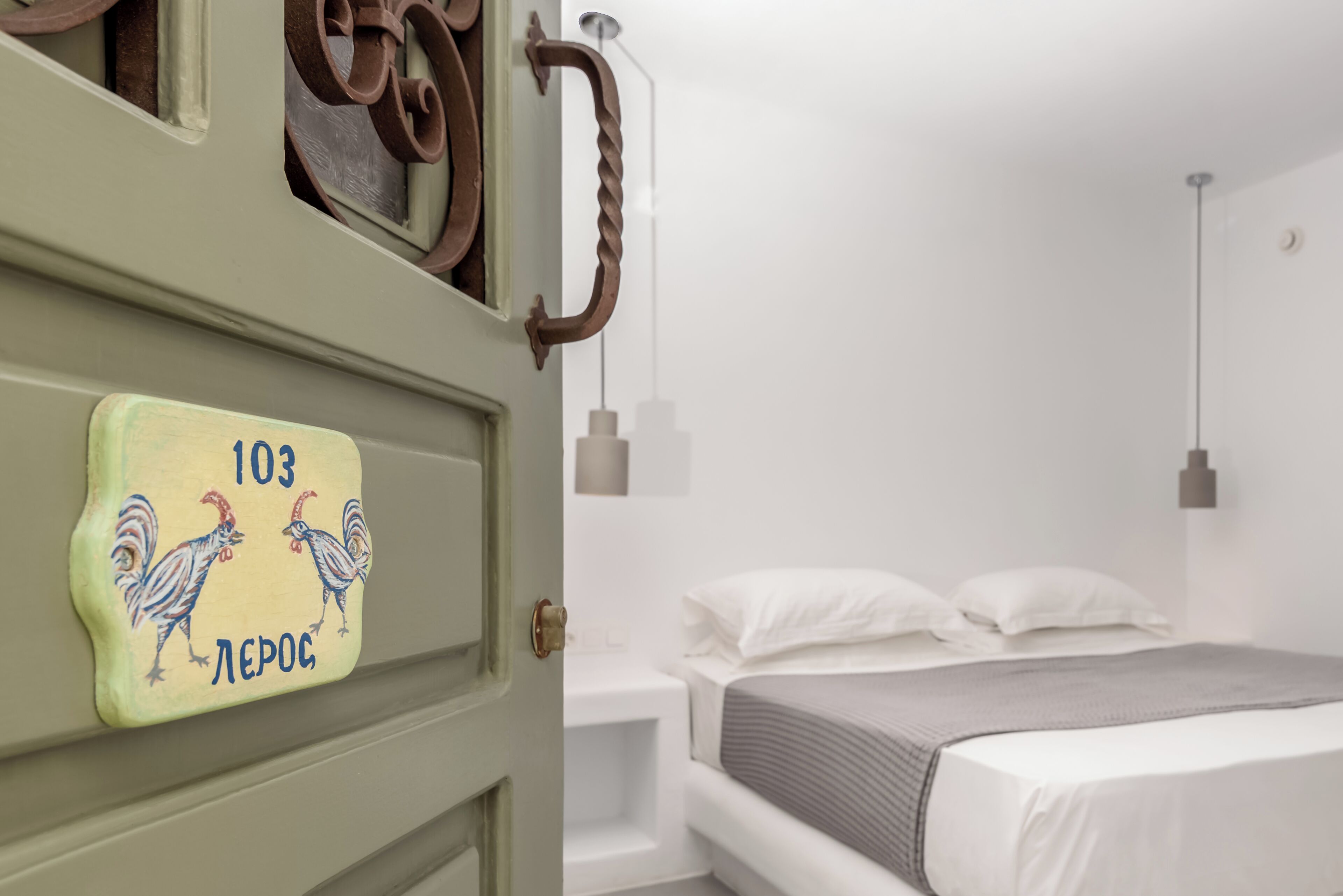 A room with a bed, a nightstand, a wall-mounted light, and a door with a number plate.