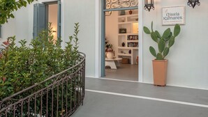 A building with a white facade, arched doorways, a potted plant, and a sign reading 'Nissia Kamares.'