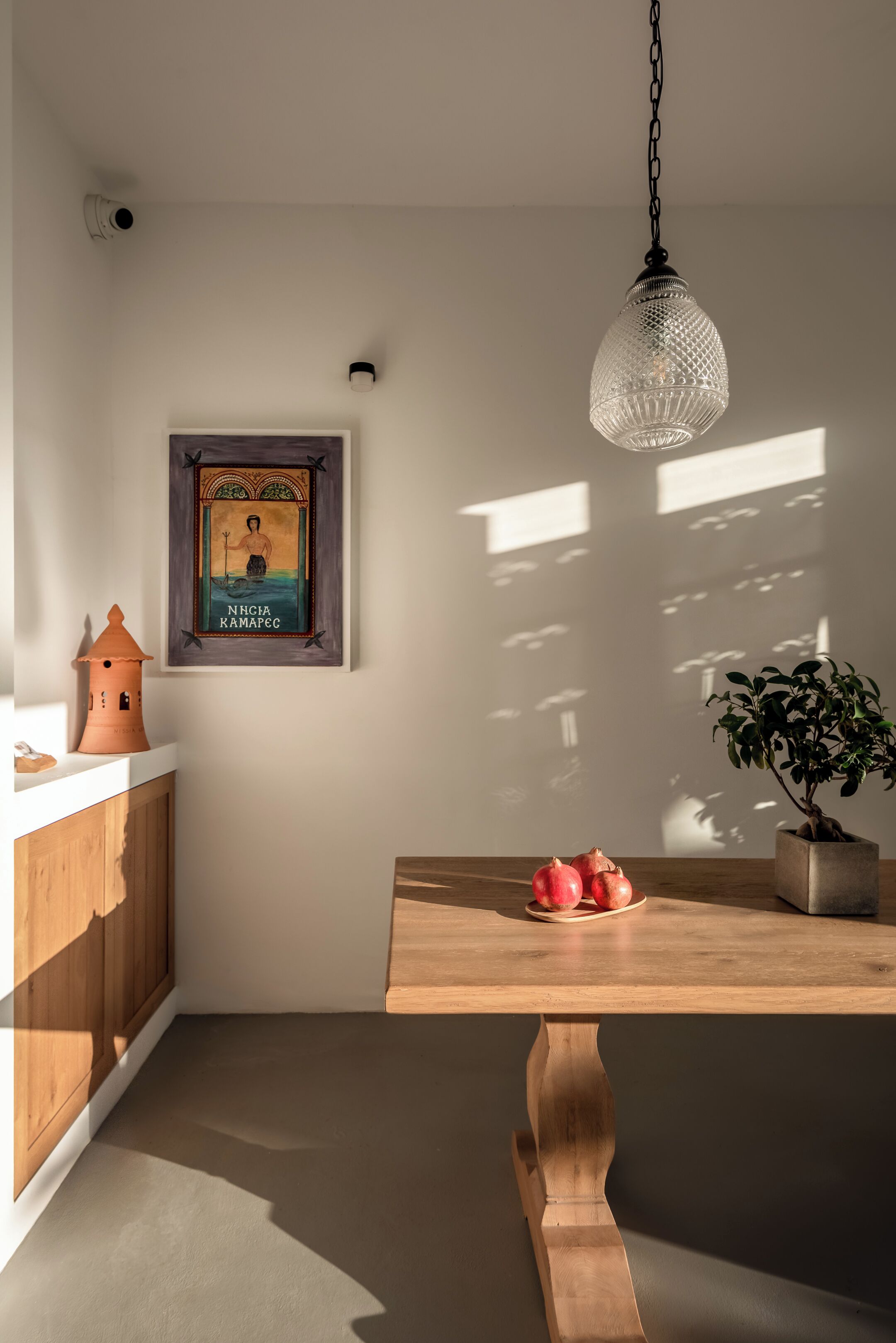 Un comedor con una mesa de madera, una planta en maceta y un adorno en la pared.