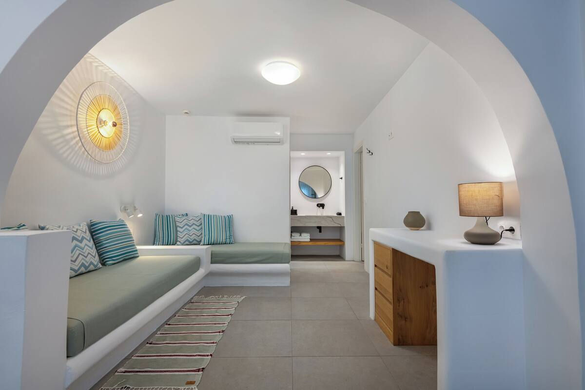 Een modern interieur met een bank, een lamp, een spiegel en een klein keukenhoekje.