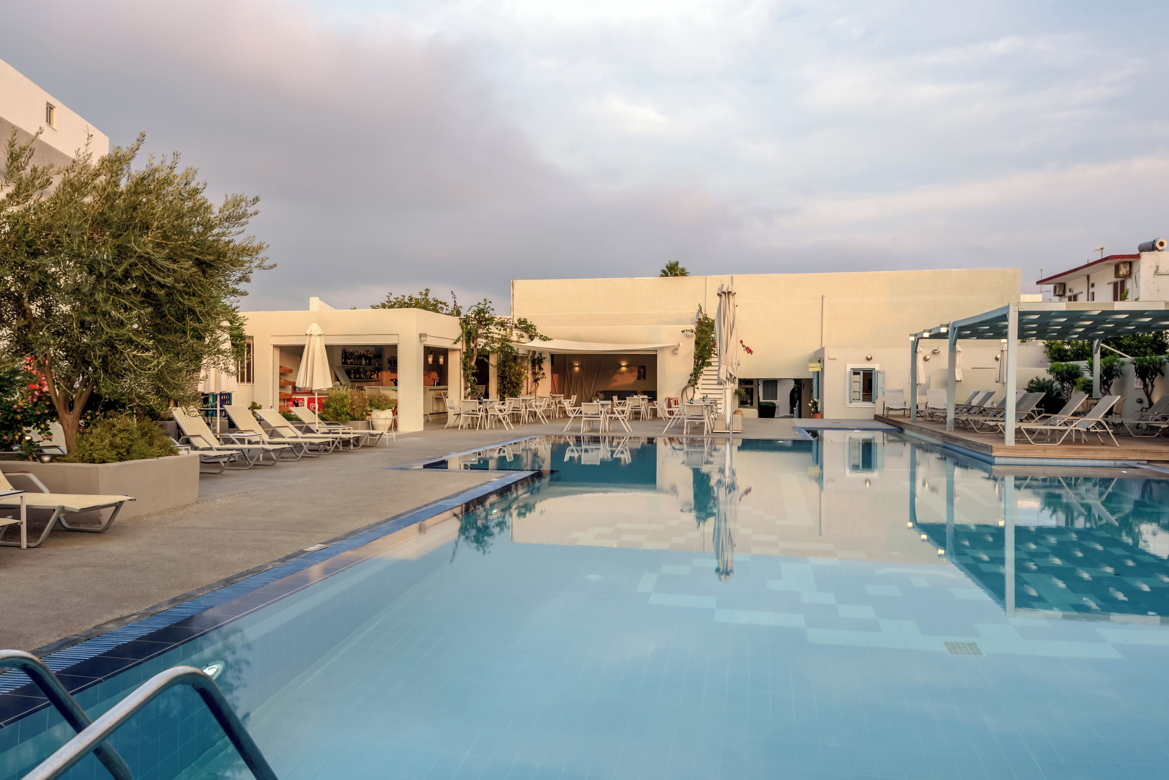 Une piscine avec des chaises longues et un espace salon abrité.