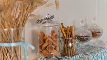 Un bocal en verre rempli de biscuits, un autre contenant des bretzels et un troisième avec des fruits secs, le tout posé sur une nappe à rayures.