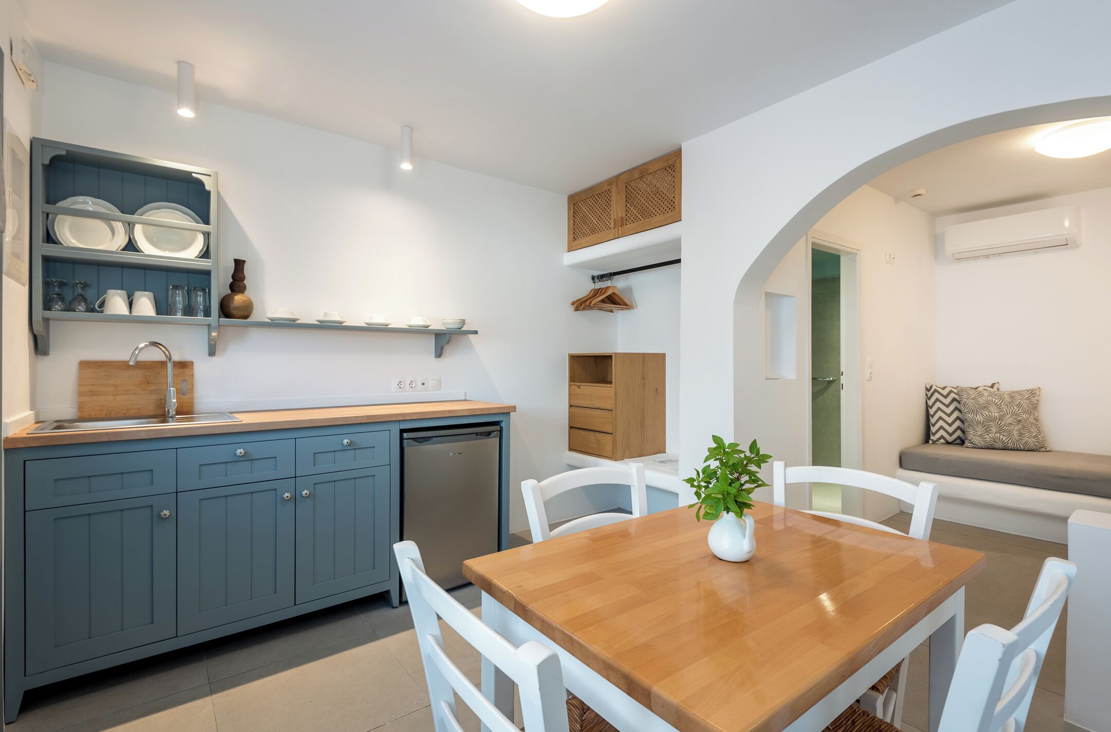 Una cocina moderna con armarios azules, una mesa de comedor de madera y sillas blancas.