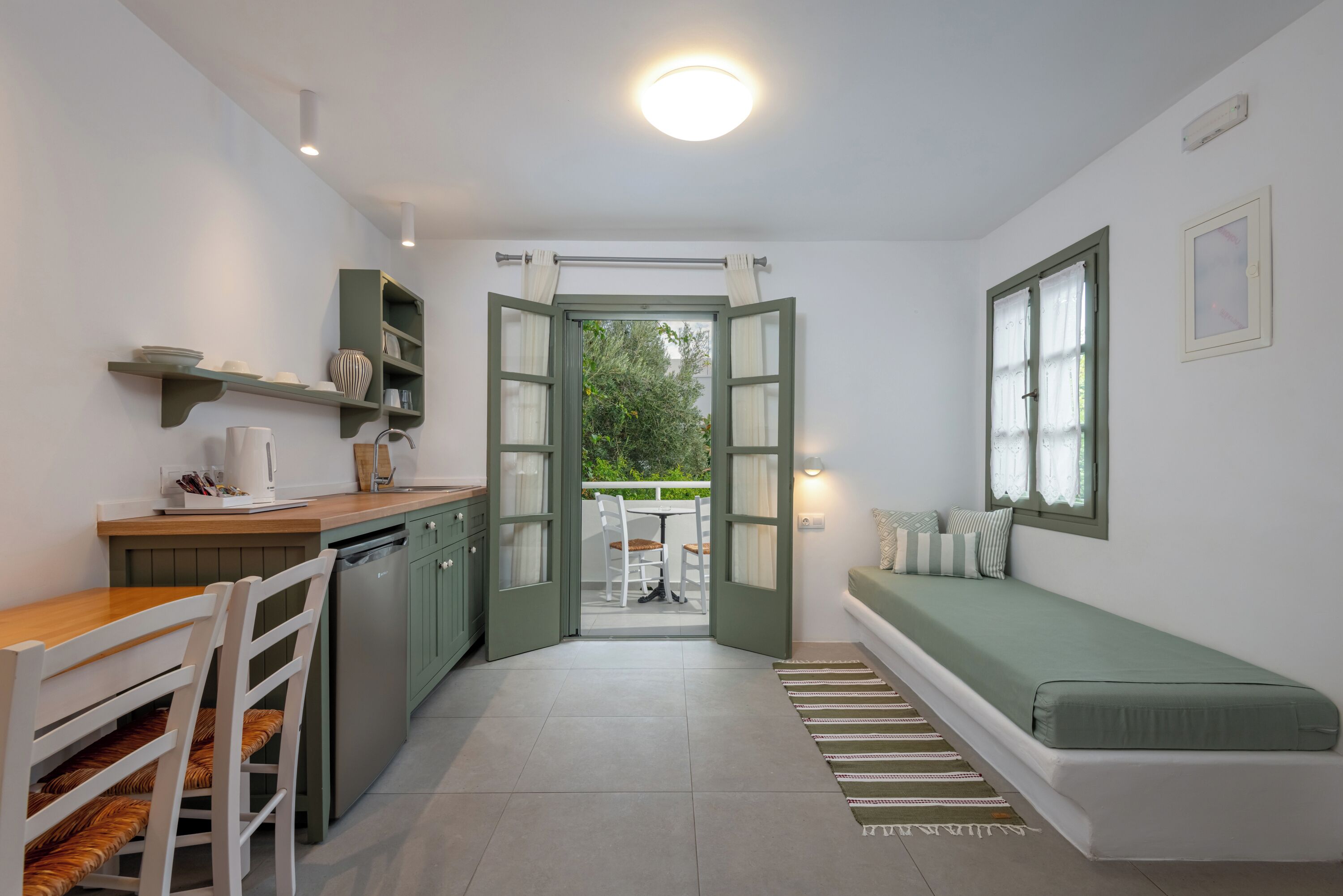 A compact kitchen with a dining area, a built-in bench, and a view through an open door.