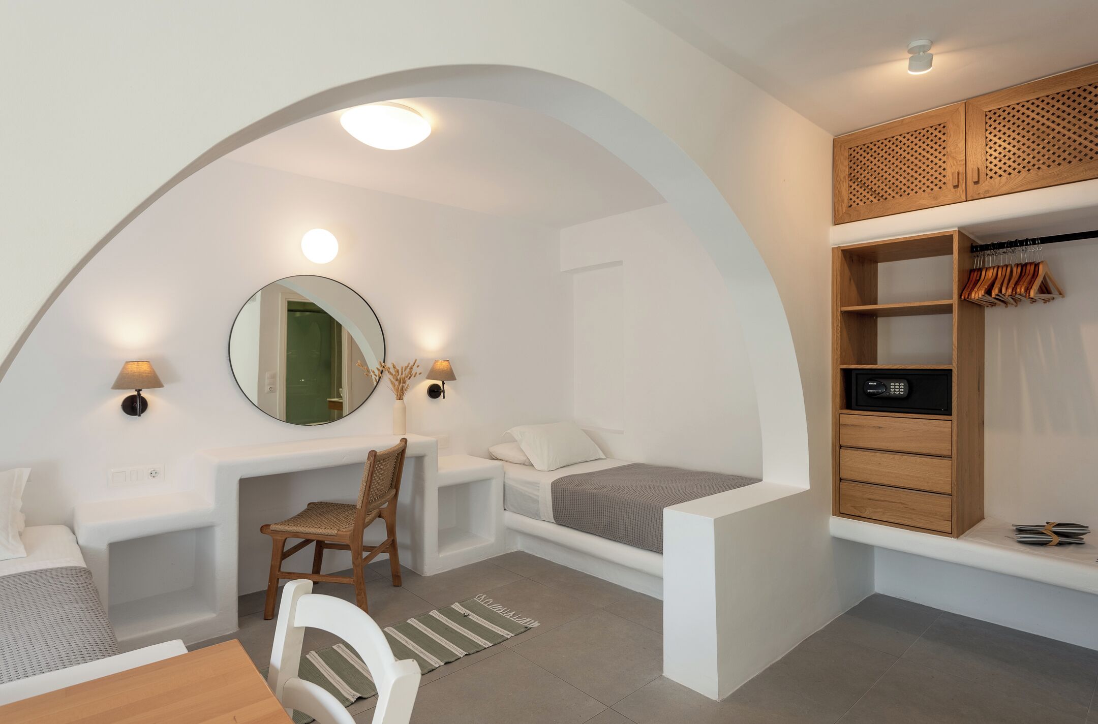 Una habitación compacta con una cama, un escritorio, una silla, un espejo, un armario y una mesita.