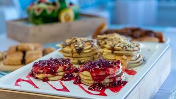 A breakfast buffet with pancakes, waffles, and pastries.