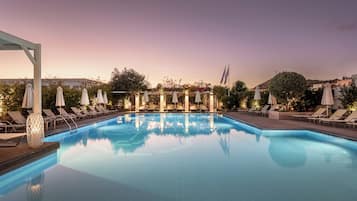 Una piscina al aire libre de temporada, sombrillas, tumbonas