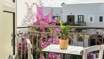 A balcony with a white table, a potted plant, and pink flowers.