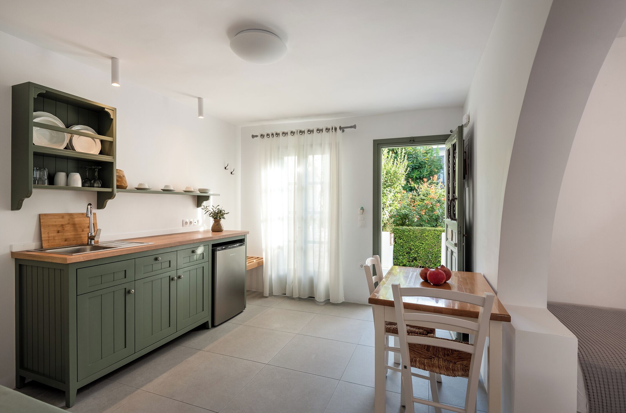 A kitchen with a wooden countertop, green cabinets, and a dining area with a table and chairs.