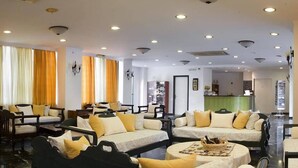 Un hall de hotel con varias zonas de estar, un mostrador de recepción y vistas al interior.
