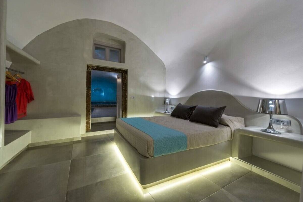 Un dormitorio con cama, mesitas de noche, una ventana y una puerta.