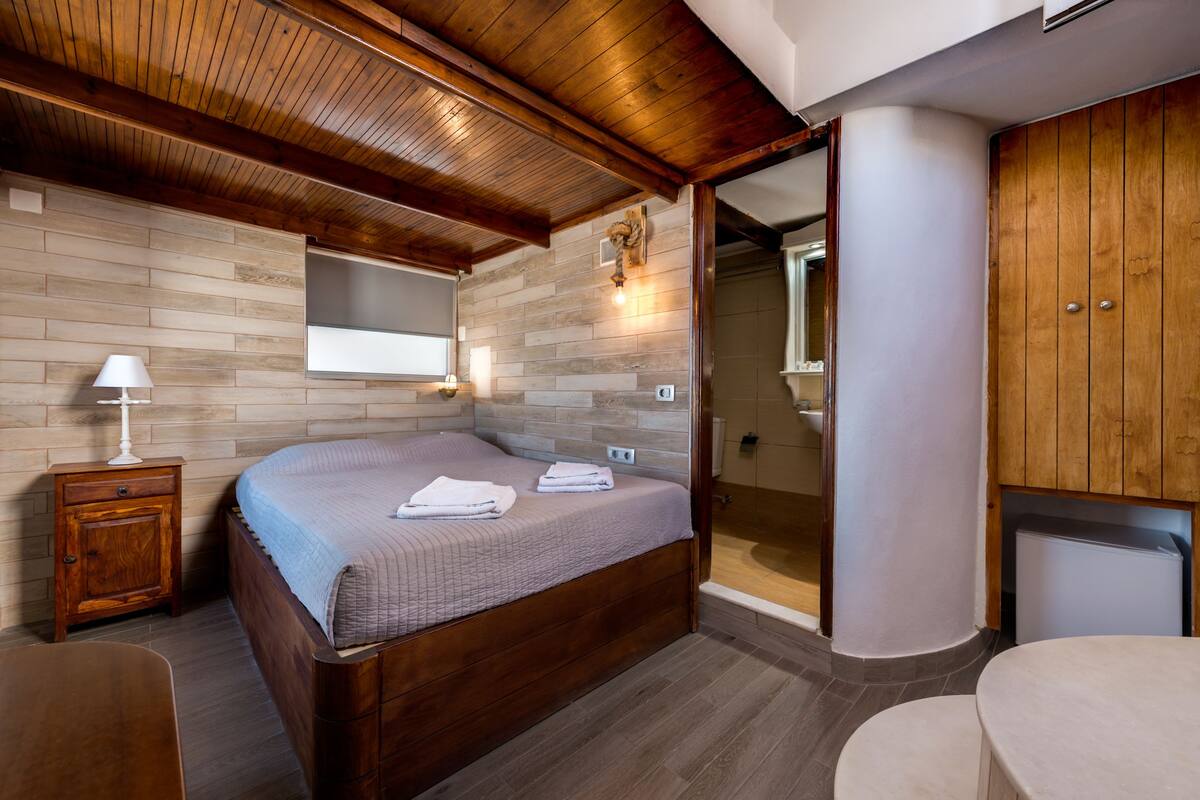Un dormitorio con una cama de madera, un mesita de noche, un tocador, un espejo y un vestidor.