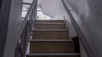 Una escalera con barandal blanco que lleva a una habitación con un ventanal grande.