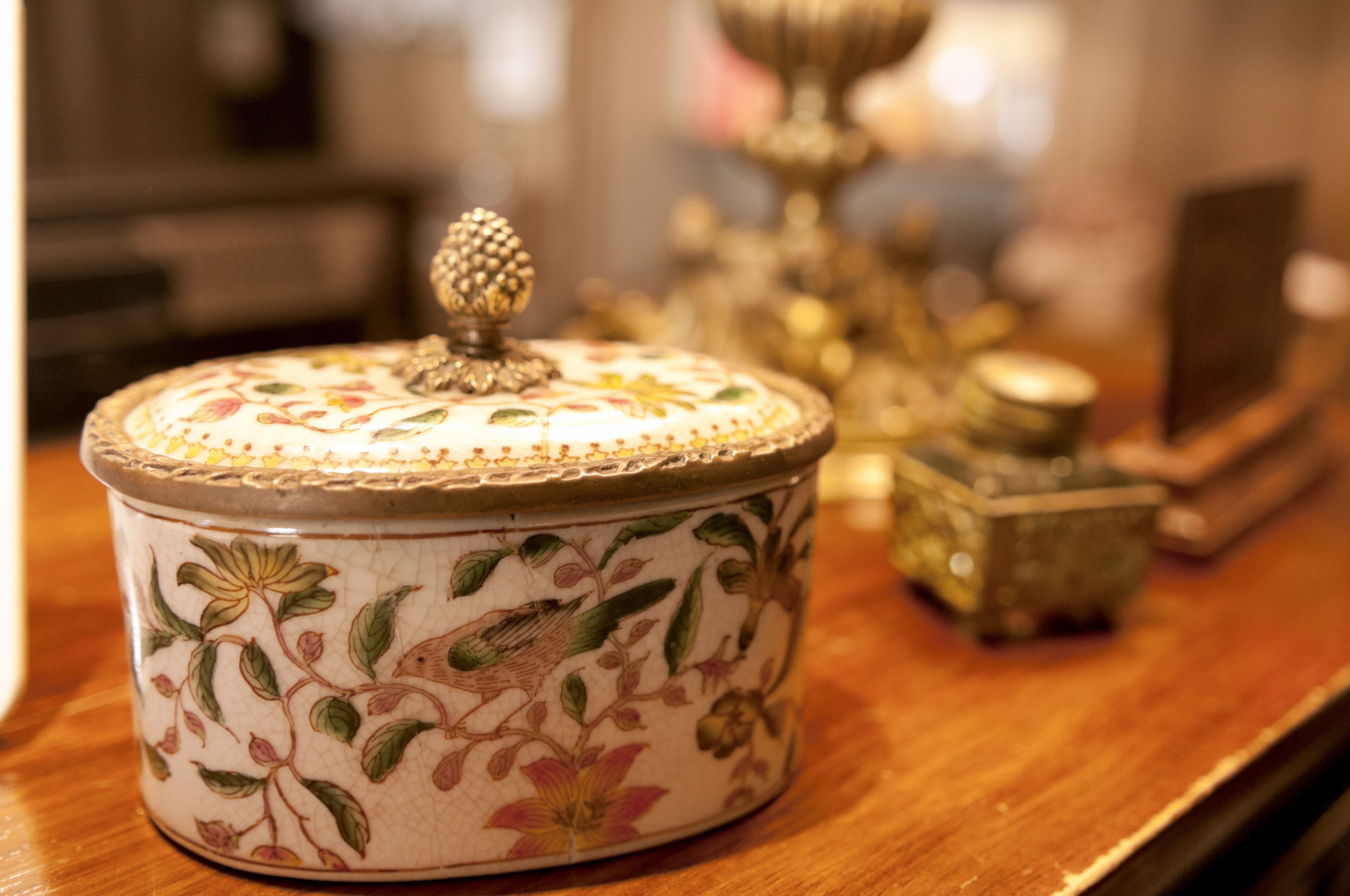 A decorative ceramic container with a floral design on a wooden surface.