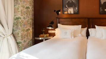 A hotel room with two beds, a nightstand with a lamp, and a wall-mounted picture.