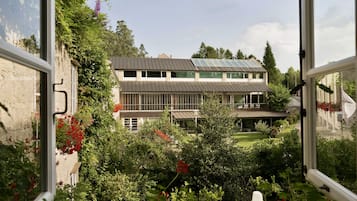 Un edificio moderno con techo plano y ventanas amplias, rodeado de vegetación exuberante y flores rojas.